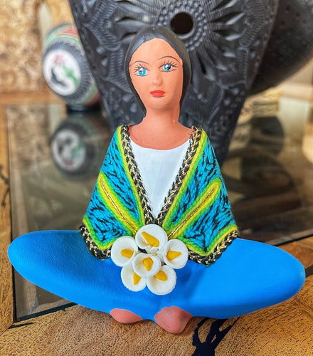 clay doll selling flowers blue and yellow shawl