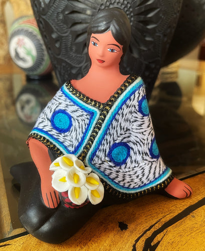 sitting clay doll selling flowers white blue shawl