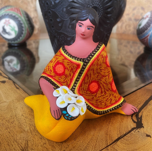 sitting clay doll selling flowers  yellow shawl