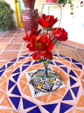 Load image into Gallery viewer, Red metal rose bouquet , placed on a patterned mosaic tile table in a patio setting.

